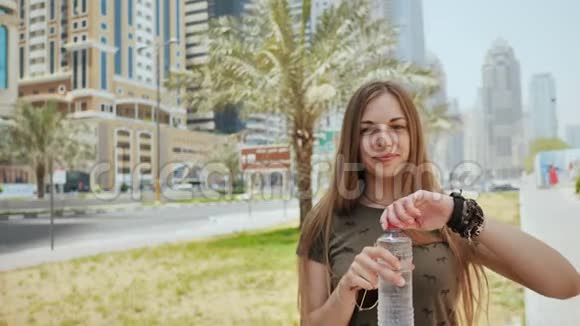 一个女孩正在迪拜市的一条街上喝一瓶水视频的预览图