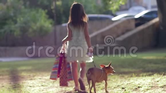 时尚的童年时尚的小女孩带着家畜走在户外参观精品店并携带视频的预览图