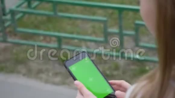 女孩手拿手机绿色屏幕视频的预览图