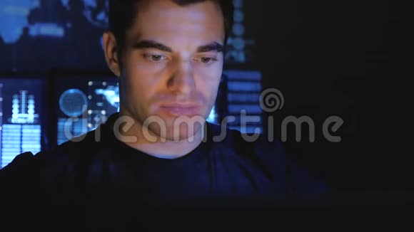 一个英俊的男性黑客程序员晚上在一个充满监控屏幕的数据中心工作视频的预览图