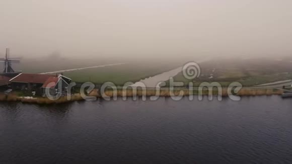 在荷兰多雾地区骑自行车的人在ZaanseSchans有风车视频的预览图
