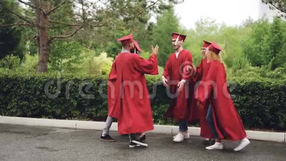 年轻男女毕业生握手击掌跳舞和拥抱的慢动作视频的预览图