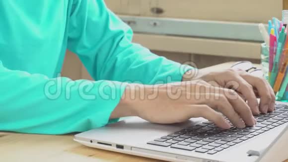 绿色t恤商人在家庭办公室打字笔记本电脑通过互联网工作和交流视频的预览图