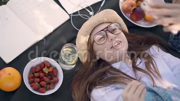 戴着眼镜的姜姑娘躺在公园的毯子上自拍视频的预览图
