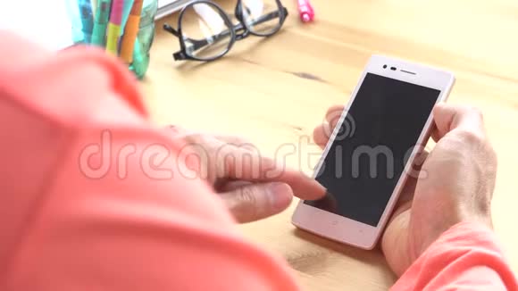玫瑰粉色t恤商人滑动变焦触摸智能手机在家庭办公室视频的预览图
