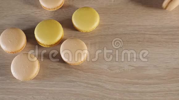 黄色和米色的马卡龙在木头背景上一个饼干卷在桌子上视频的预览图