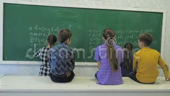 小学小女生在教室的绿色黑板上写数字视频的预览图