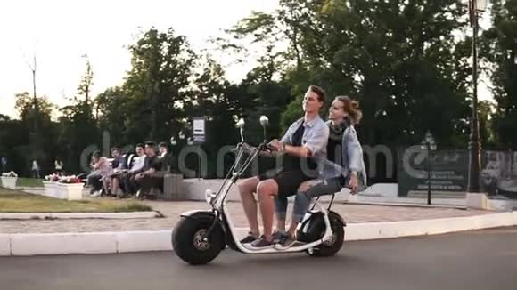 年轻人和她的女朋友正在拥挤的绿色公园里骑着电动胆汁穿着休闲装快乐的时刻视频的预览图