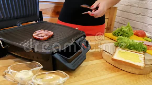 在厨房里做三明治用钳子夹着一块刚烤过的热肉从烤架和烤架上看到视频的预览图
