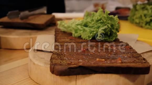 在厨房里做三明治用酱汁抹上油炸黑面包的特写镜头上面放着一片绿叶的生菜视频的预览图