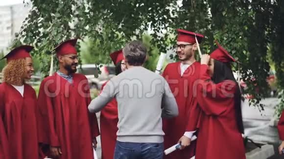 大学老师抱着学生的慢动作带着喜悦和自豪在毕业的日子里握手绿树树视频的预览图
