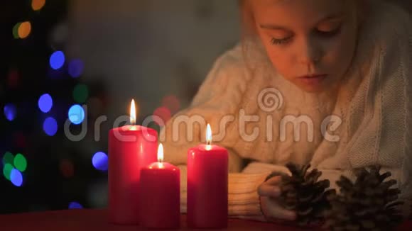 可爱的女孩在蜡烛旁玩松果圣诞节视频的预览图