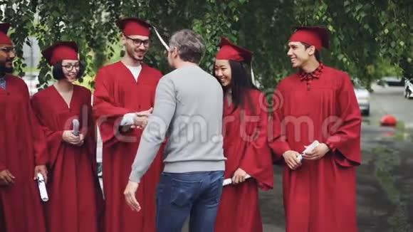 骄傲的大学老师慢悠悠地拥抱学生握手即将毕业的学生站在队伍中视频的预览图