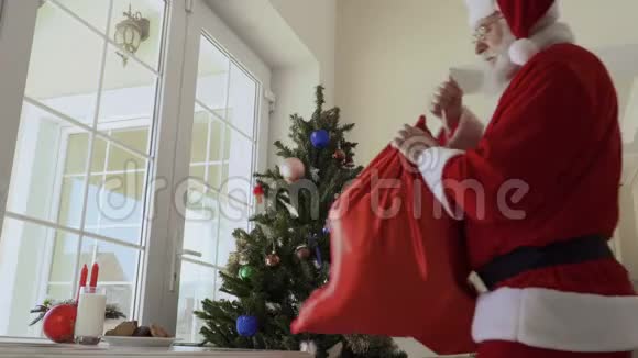 圣诞老人品尝饼干把包里的礼物放在桌上视频的预览图