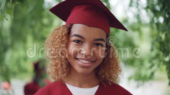 身穿红色长袍站在户外的漂亮非裔美国女毕业生慢镜头肖像视频的预览图