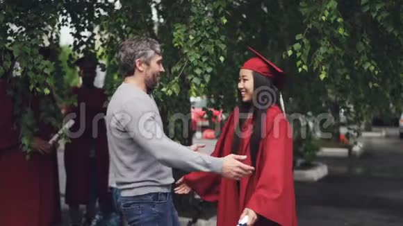 爱的父亲是在祝贺女儿毕业的日子人们在户外拥抱和欢笑而其他人视频的预览图