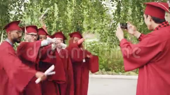 一位拥有智能手机的年轻人正在为毕业生拍照他们拿着毕业证书手手手指和视频的预览图