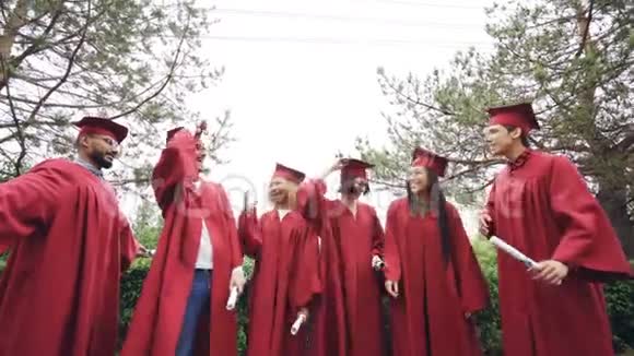 在大学校园里快乐的毕业生在空中抛掷灰泥板欢笑和庆祝毕业视频的预览图