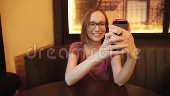漂亮的女孩用智能手机自拍做脸和乐趣视频的预览图