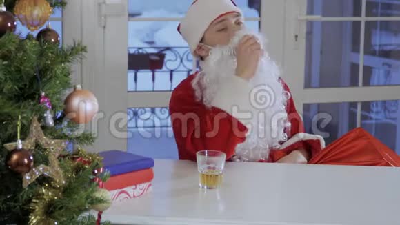 酒醉的圣诞老人坐在桌旁喝威士忌视频的预览图