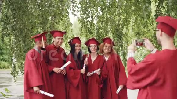 毕业学生中的许多人都在为智能手机相机摆姿势挥舞着带毕业证书的双手大喊着视频的预览图