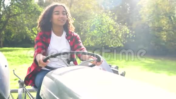 穿着灰色拖拉机穿过阳光明媚的苹果园的少女视频的预览图