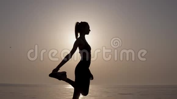 日出天空背景上的女人黑色剪影年轻活跃的女孩站着做垂直的麻绳伸展以保持视频的预览图