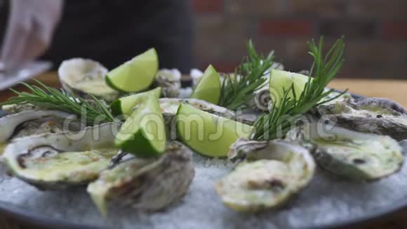 食品成分及设计用奶酪草药和石灰烤的牡蛎放在盘子里海鲜背景视频的预览图