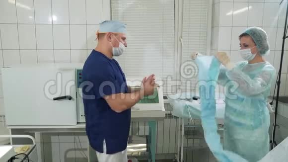 无菌手术室医生正在准备手术护士帮他穿上一件特殊的长袍和手套视频的预览图