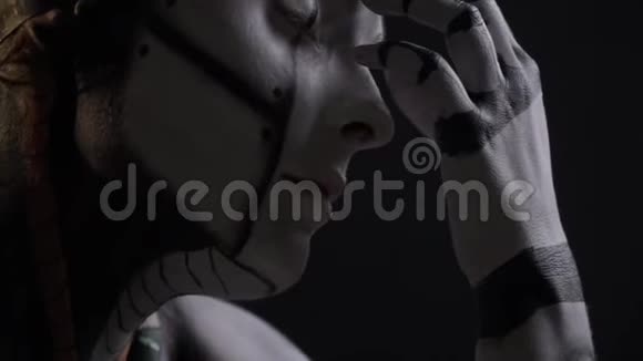 一个机器人女人在黑色背景上摸她的鼻子和嘴唇视频的预览图