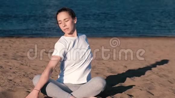 女人在城市河边的海滩上伸展瑜伽美丽的景色把头倾斜到一边视频的预览图
