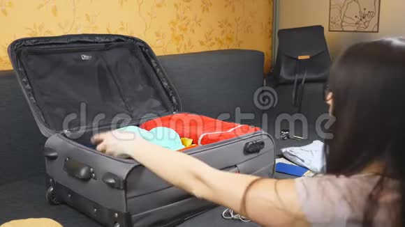 女人在她房间里的沙发上装着私人物品的手提箱女士准备好乘飞机去度假女孩视频的预览图