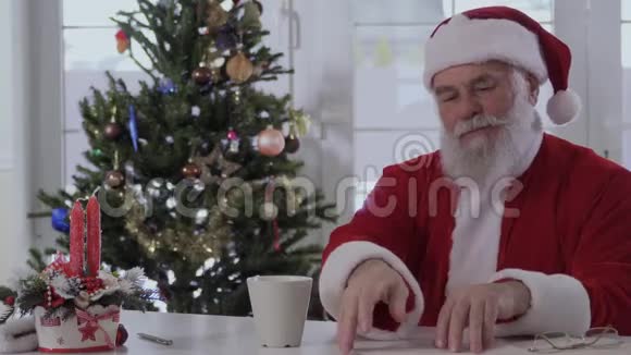 圣诞老人在圣诞树附近的桌子上念祝福信视频的预览图