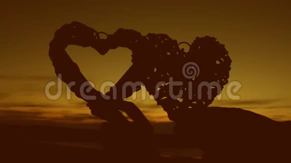 可爱的一对在日落时捧着心浪漫的蜜月瓦伦丁戴特写视频的预览图