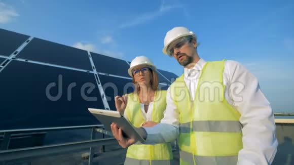 两位太阳能专家一边走路一边操作平板电脑视频的预览图