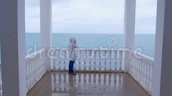 穿着白色夹克的女人在美丽的露台上拍摄海浪视频后景视频的预览图