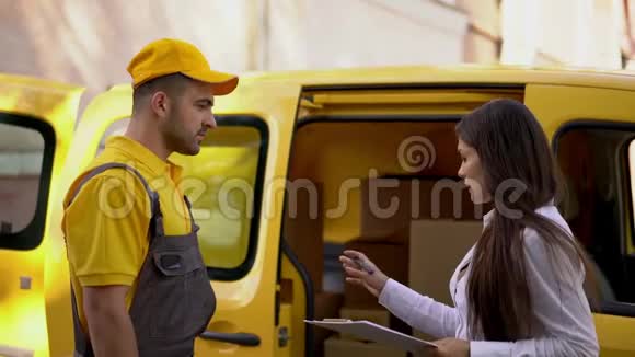 女商人在他的车附近的室外检查由黄色制服的快递员送货视频的预览图