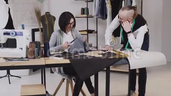 团队合作的两个裁缝和裁缝谁是微笑和工作缝纫一个新的收藏女裁缝雕刻了一个视频的预览图