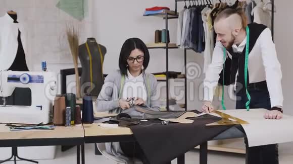 团队合作的两个裁缝和裁缝谁是微笑和工作缝纫一个新的收藏女裁缝切割图案视频的预览图