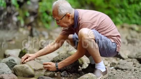 老人在户外的岩石上擦玛瑙视频的预览图