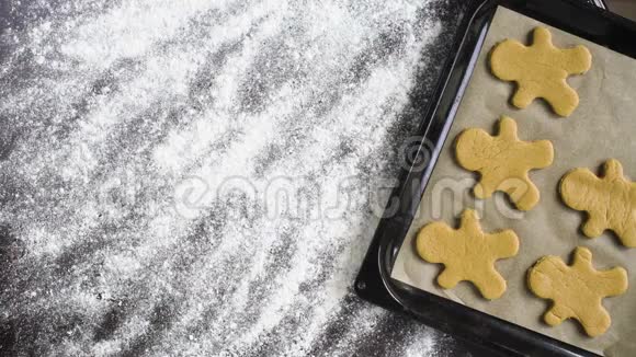 圣诞节词出现在面粉覆盖的桌子上烤盘上有姜饼人饼干视频的预览图