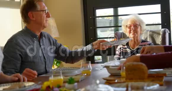 高级男子为餐桌上的妇女提供餐盘视频的预览图
