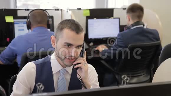 这位年轻的男性财务顾问在工作场所与客户进行电话交谈视频的预览图