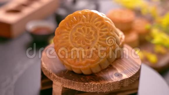 美丽的月饼在木制托盘上旋转黑色石板背景上有茶和花中国传统中秋节视频的预览图