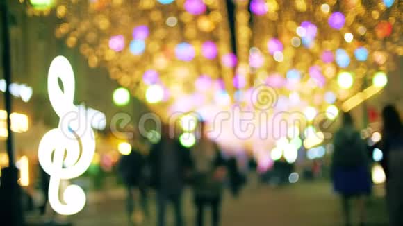 傍晚模糊的人们沿着灯火通明的步行街散步视频的预览图