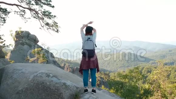 一位女士举着双臂站在山顶看着风景远足的女孩举起手臂庆祝风景视频的预览图