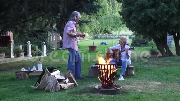 那人手里拿着一杯酒迎接妻子期待着篝火旁的音乐之夜视频的预览图