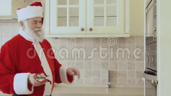 圣诞老人从烤箱里拿出烤盘和新鲜饼干视频的预览图