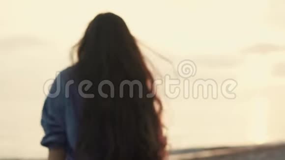 一个年轻的女人跑到海边晚上海浪拍打着海滩视频的预览图
