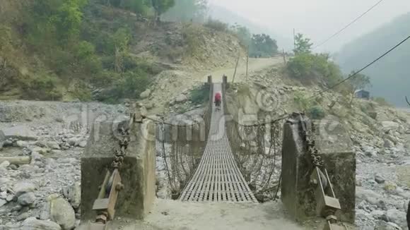两个背包客沿着尼泊尔的一座悬挂的金属桥视频的预览图